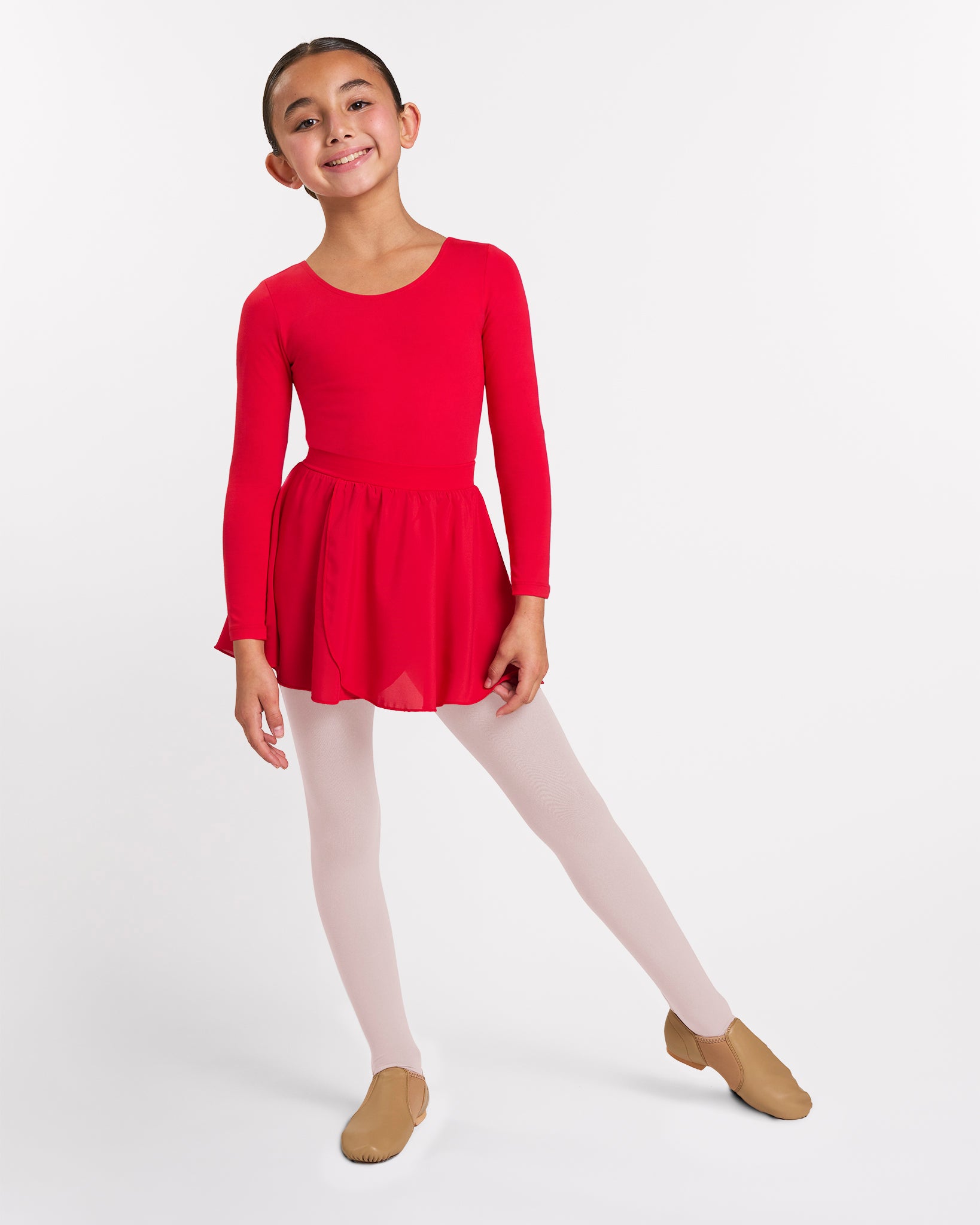 Girl wearing a red long sleeve ballet leotard with matching pull-on skirt, ballet pink tights, and tan ballet shoes.