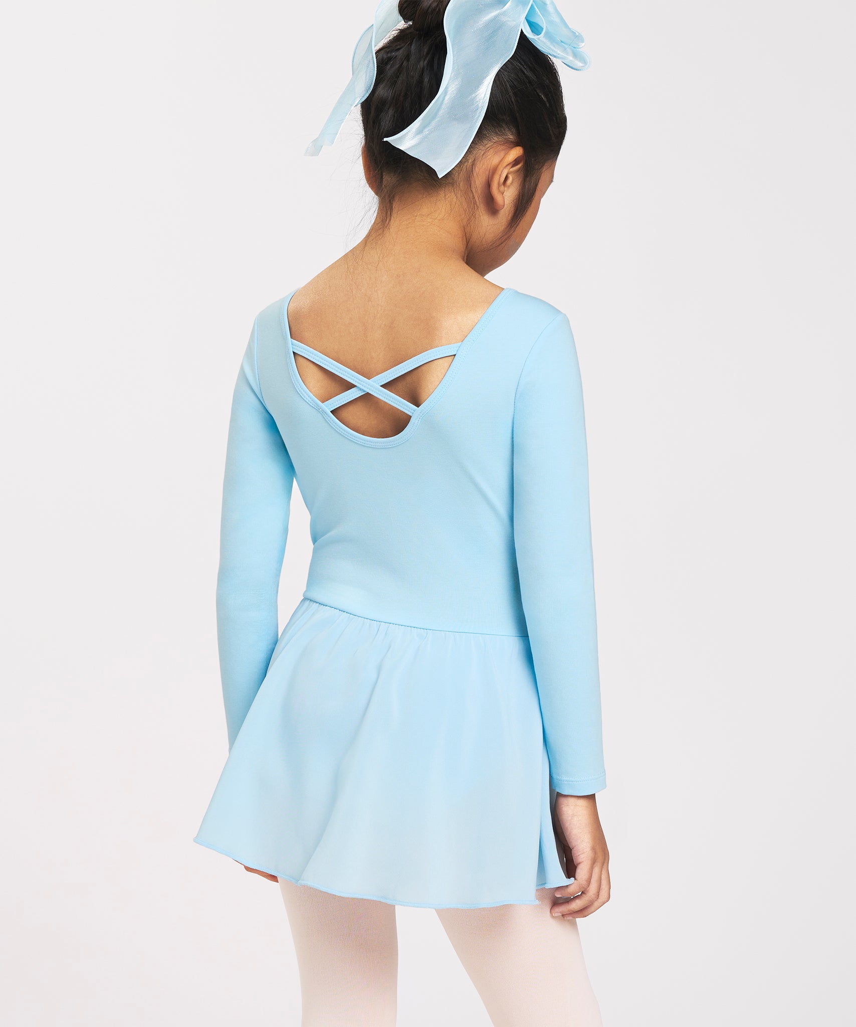 Back view of girl wearing a blue ballerina dress with long sleeves, crisscross back detail, chiffon skirt, and bow accent.