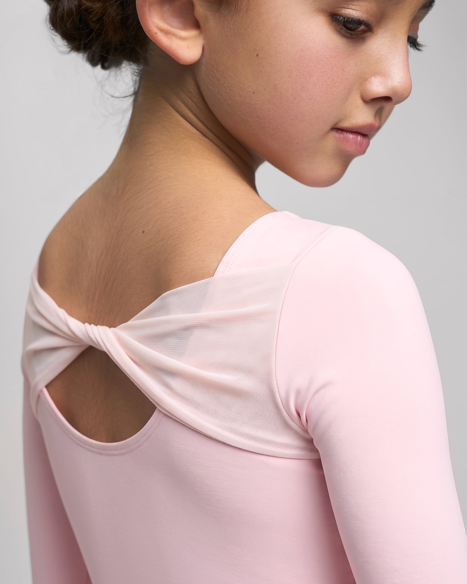 Close-up of Ballet Pink girls performance leotard showing the twisted mesh back detail and open scoop-back design.