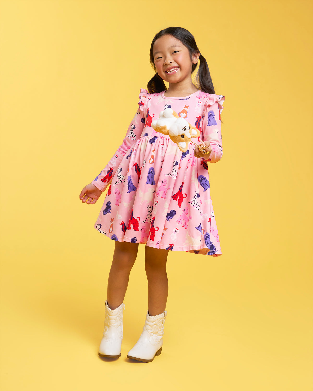 Girl wearing a Puppy Parade on Pink long sleeve dress with ruffle shoulders, gathered waist, A-line skirt, and white shoes.
