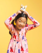 Close-up of girl wearing a Puppy Parade on Pink long sleeve print dress showing ruffle shoulder details and colorful in-house puppy graphics.