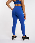 Back view of blue high-waisted leggings showing smooth fit, side pocket seams, and full-length activewear design.