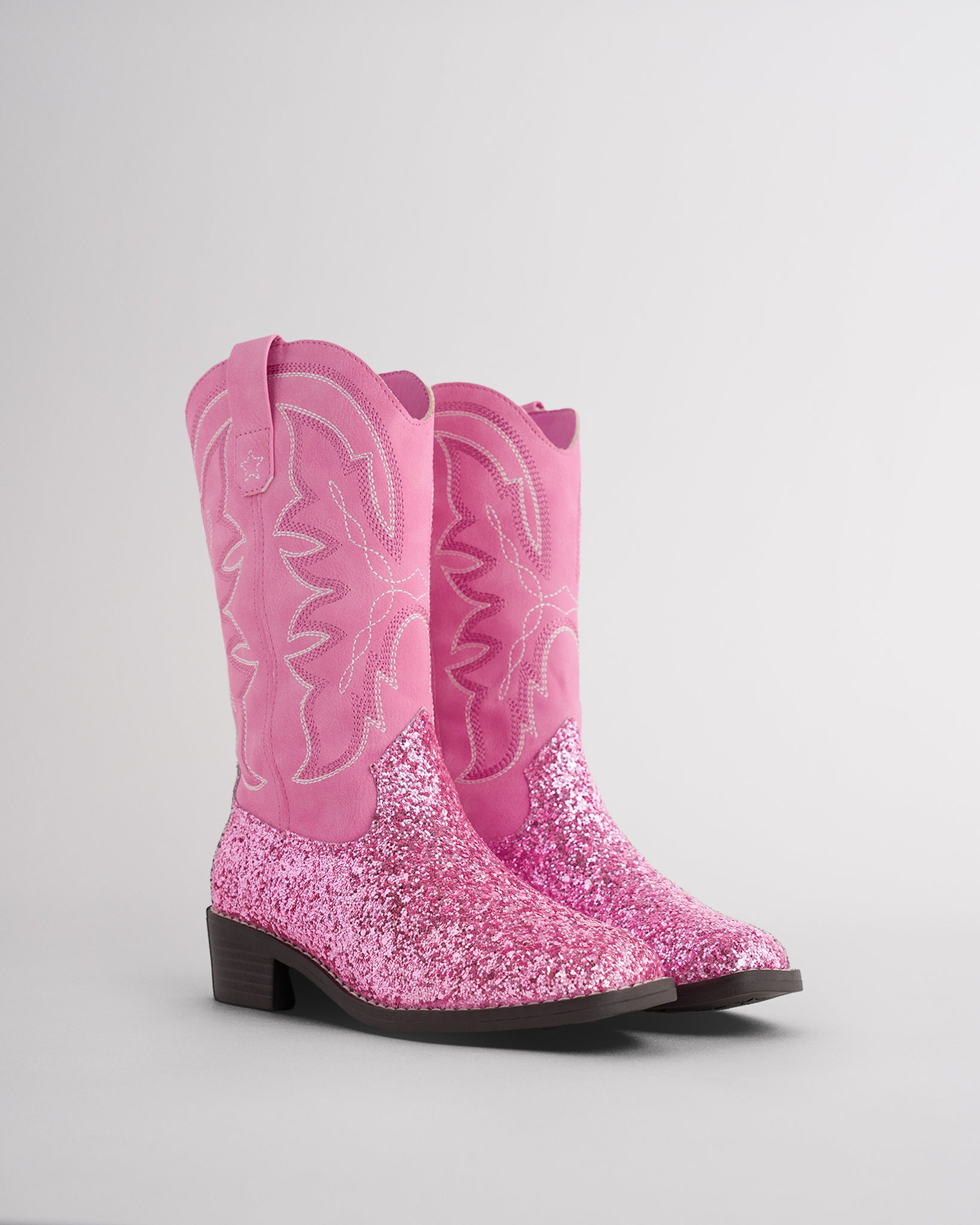 Pair of pink glitter cowgirl boots for toddlers and kids with embroidered western stitching
