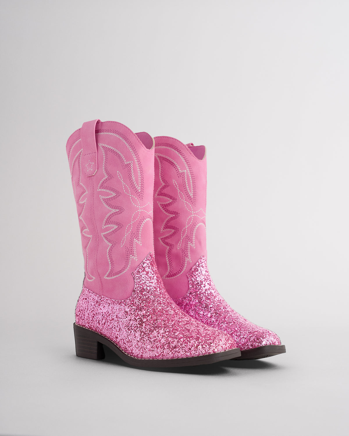 Pair of pink glitter cowgirl boots for toddlers and kids with embroidered western stitching