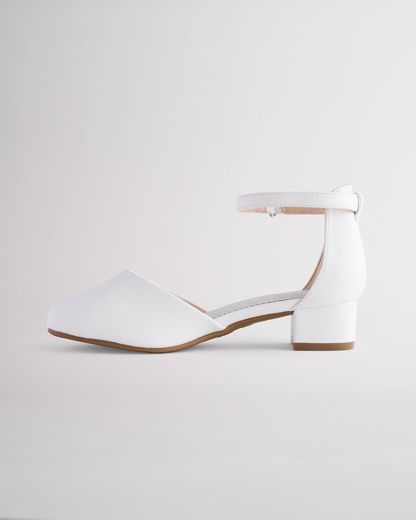 Girls’ white dress shoes with a low block heel and ankle strap.