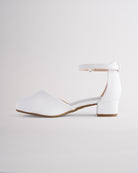 Girls’ white dress shoes with a low block heel and ankle strap.