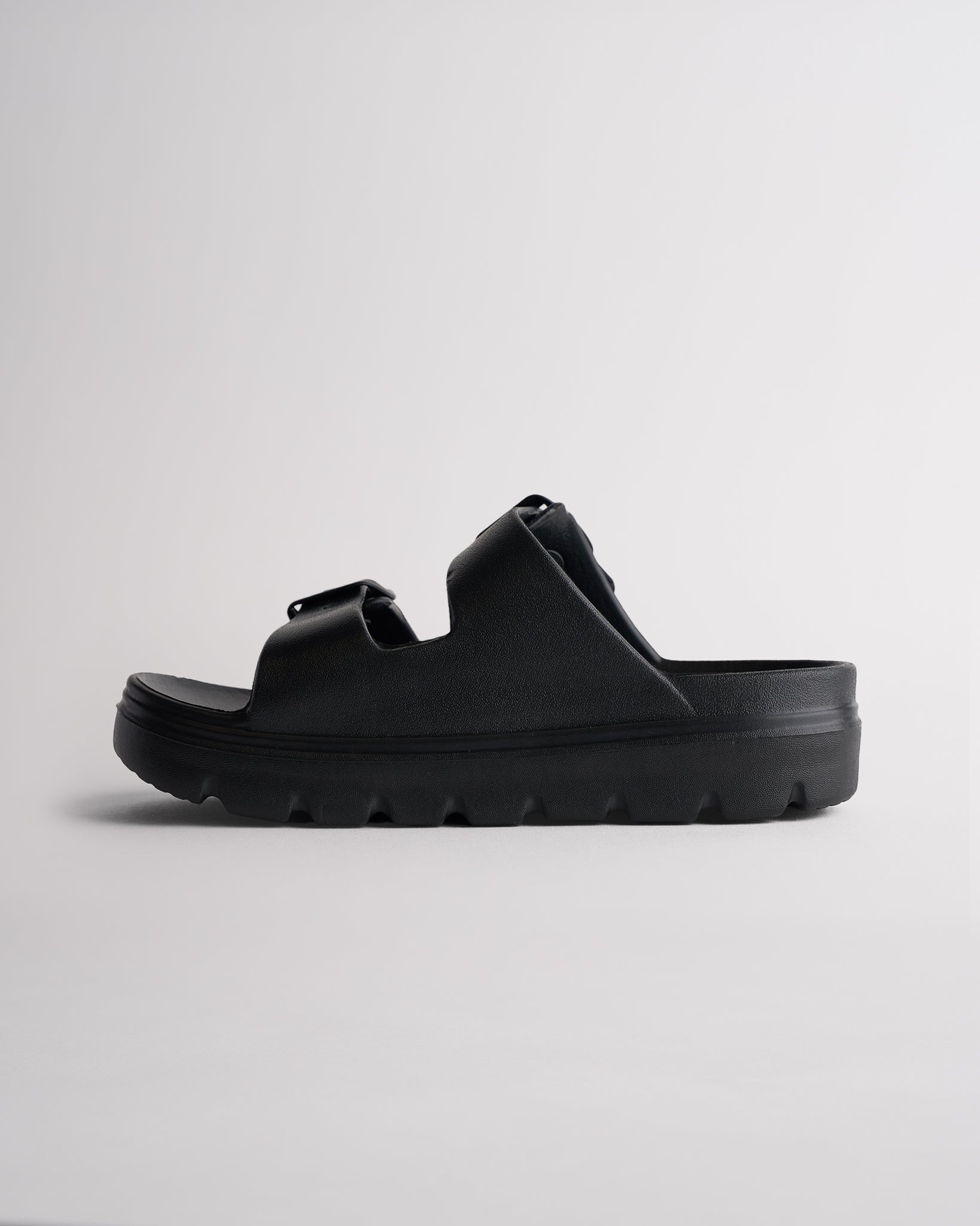 Side view of black Stelle Kids StelleCloud Buckled Slide showing the easy slide-on design, raised sole, and adjustable straps.