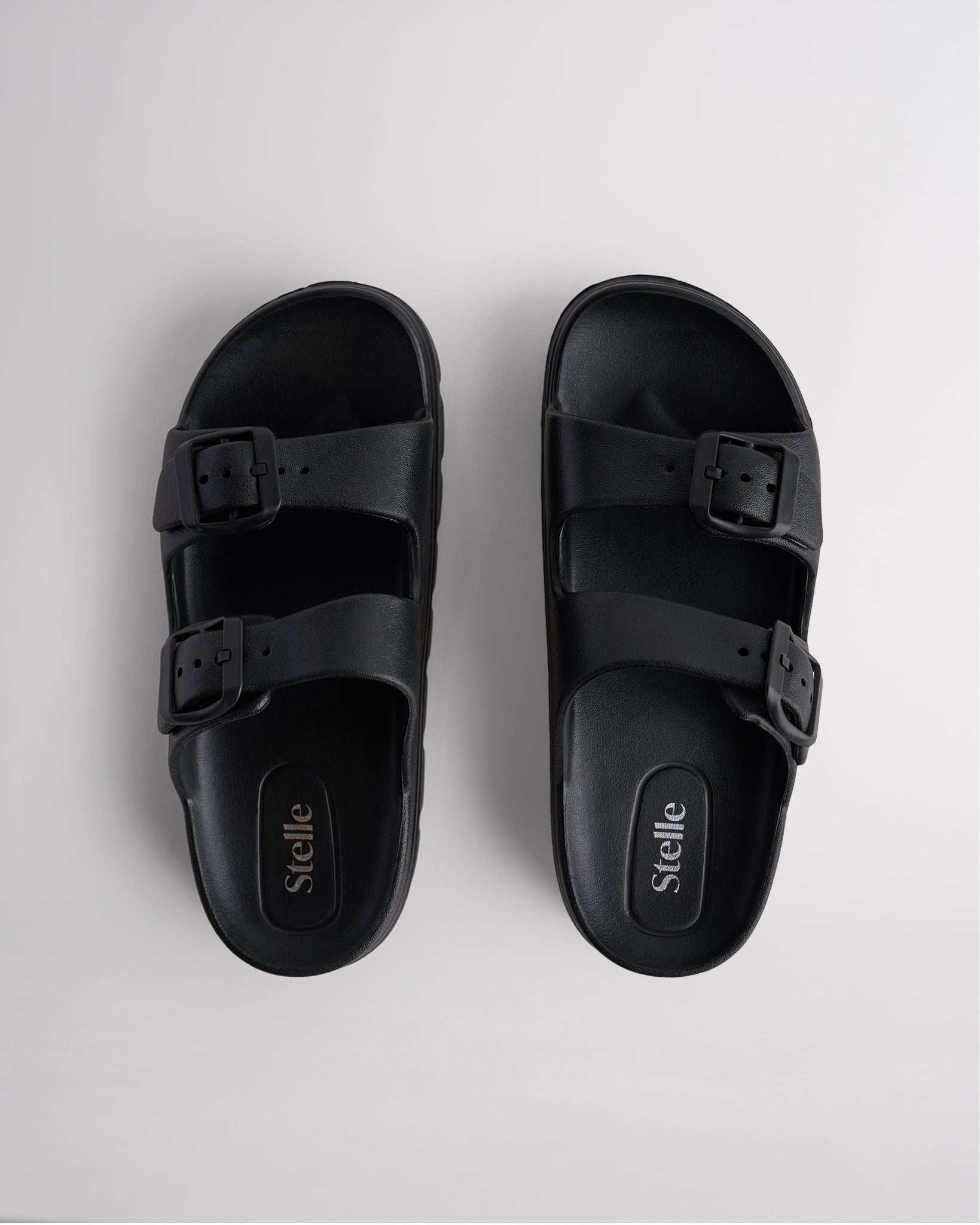 Top view of black Stelle Kids StelleCloud Buckled Slide with two buckle straps, contoured footbed, and Stelle logo detail.
