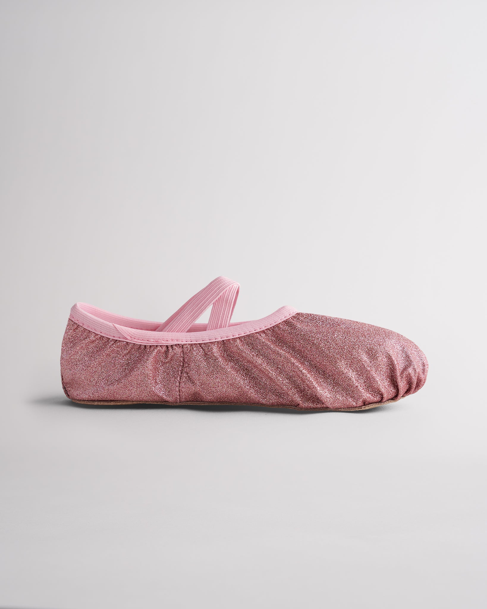 Kids glitter ballet shoes in rose glitter with elastic straps, side view
