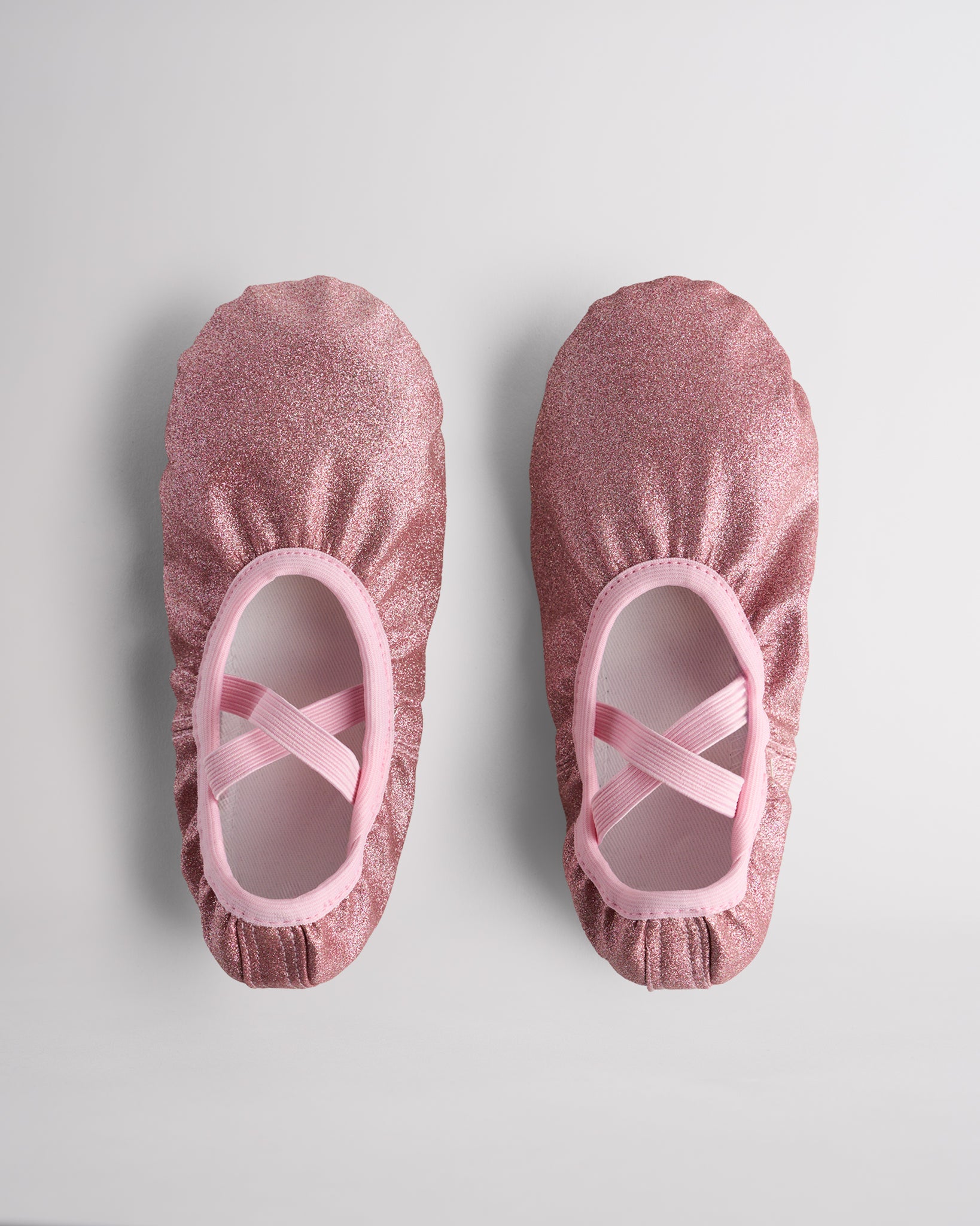 Kids glitter ballet shoes in rose glitter with crisscross elastic straps, top view
