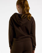 Back view of a woman wearing the brown Coffee Stelle fleece-lined zip-up hoodie with the hood down.