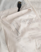 Close-up of a beige heated vest with text and a USB cable.