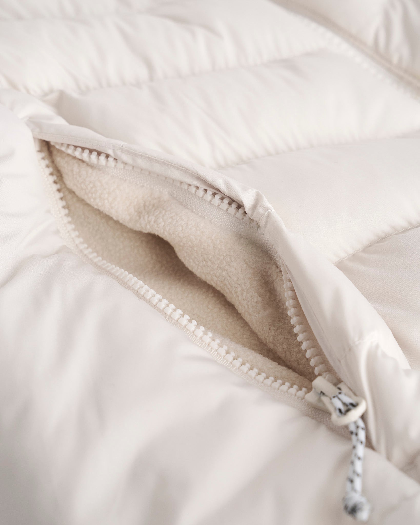 Close-up of a white jacket with a zipper, showing the interior lining.