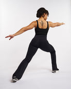 Model wearing black Stelle flare leggings with pockets in a workout pose, showing flexible fit and flared legs