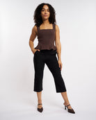 Woman wearing black high-rise stretch capri pants with straight-leg fit styled with a brown sleeveless top.