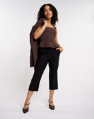 Woman styling black high-rise capri pants with a brown top and blazer for a polished casual look.