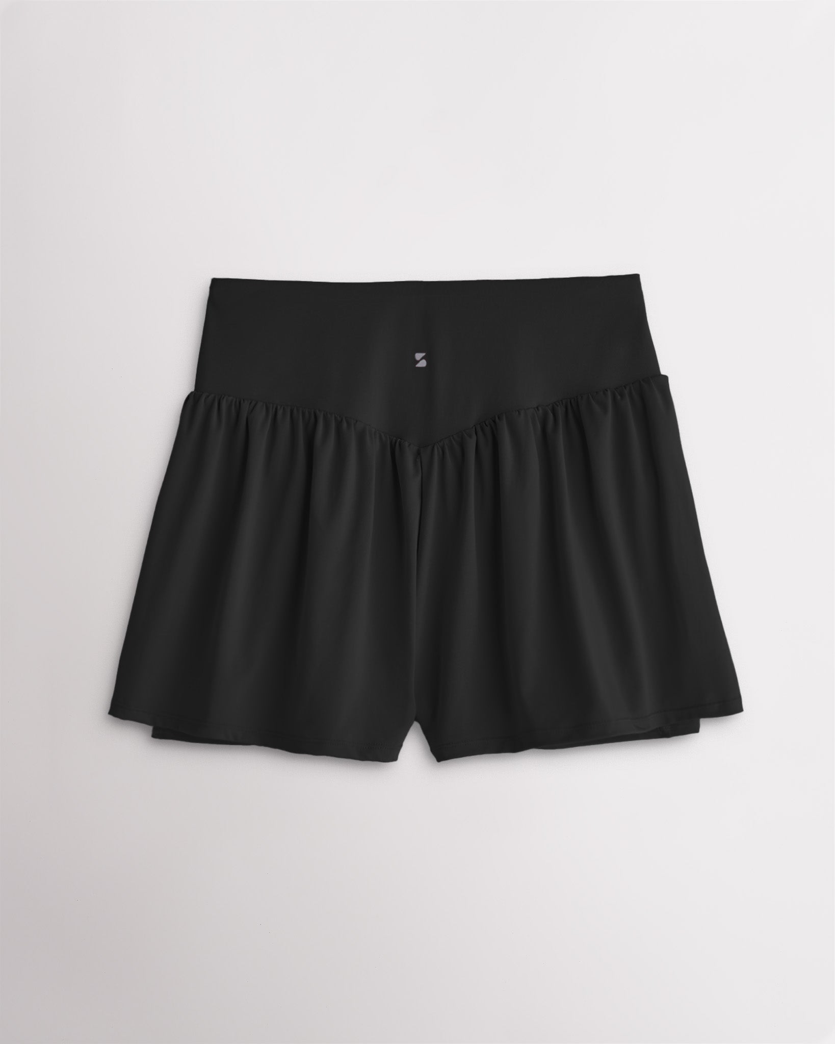 Back view of women’s black high waisted athletic shorts with a flowy layered design and V-contour back seam.