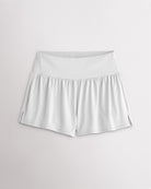 Women’s white 2-in-1 high waisted athletic shorts with a flowy outer layer, built-in shorts, and side slit detail.