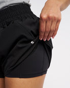 Close-up of black 2-in-1 running shorts showing the inner shorts lining and pocket detail.