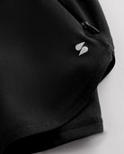 Close-up of black Stelle gym shorts showing zipper pocket, curved hem stitching, and smooth performance fabric.