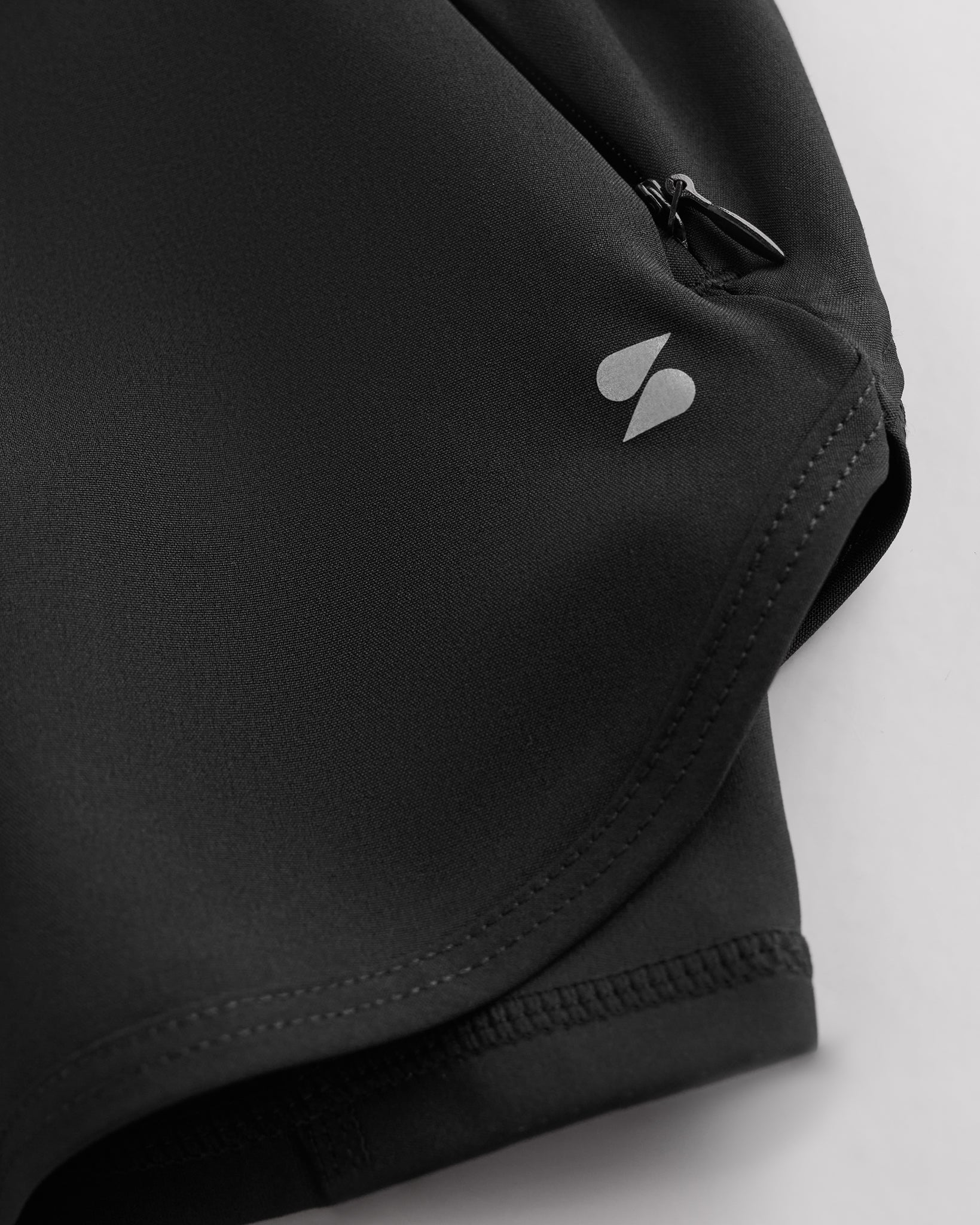 Close-up of grey Stelle gym shorts showing zipper pocket, curved hem stitching, and smooth performance fabric.