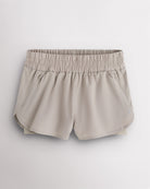 Sandy Grey Stelle RushMode 2-in-1 running shorts with wide elastic waistband, zipper pockets, inner shorts lining, and curved dolphin hem.