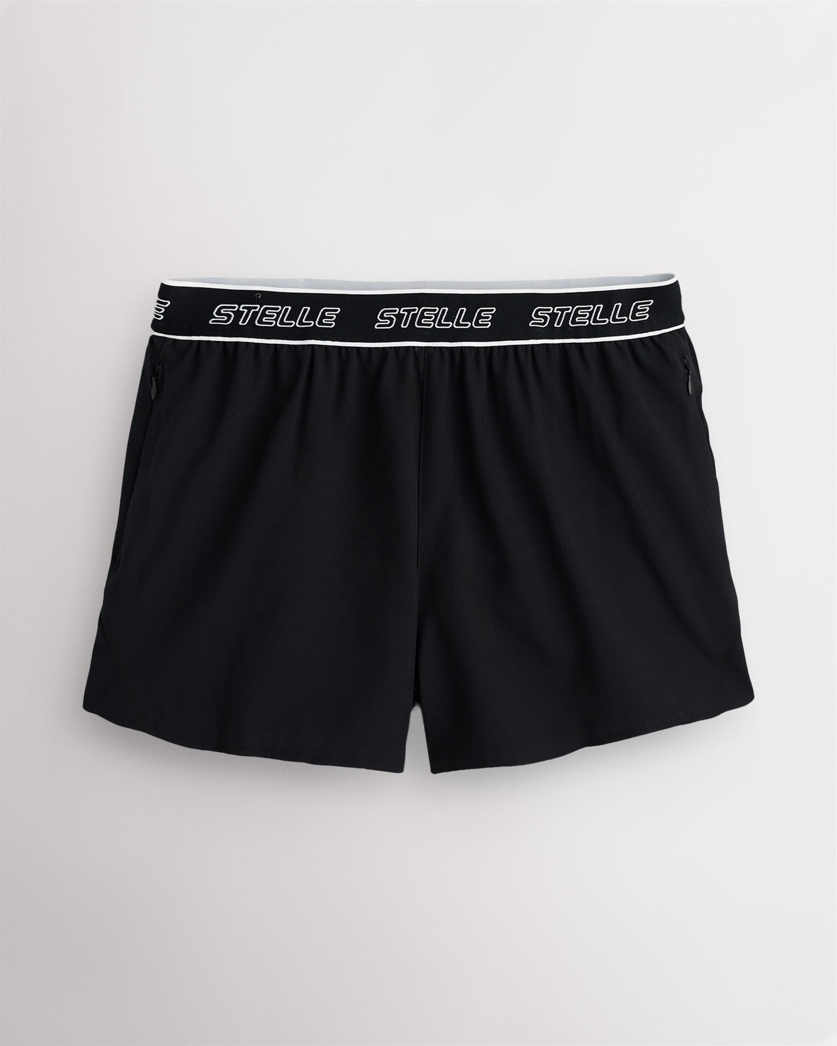 Black Stelle women's running shorts with a white logo waistband, laid flat on a grey background.