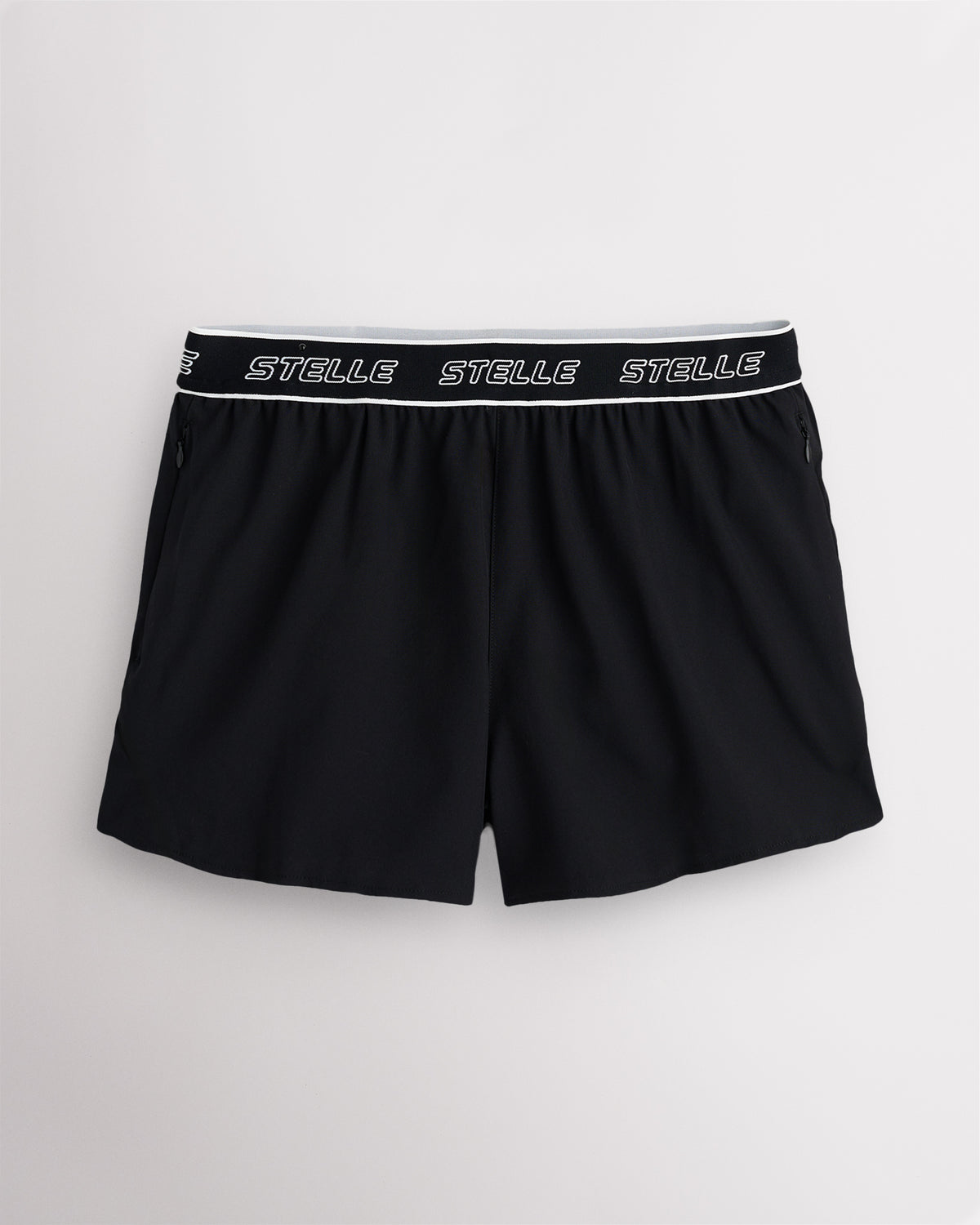 Black Stelle women's running shorts with a white logo waistband, laid flat on a grey background.