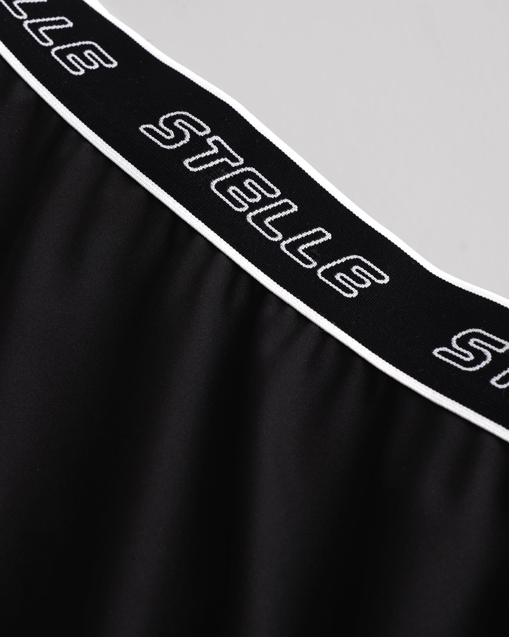 Close-up of the white Stelle logo elastic waistband on the black running shorts.