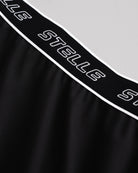 Close-up of the white Stelle logo elastic waistband on the black running shorts.