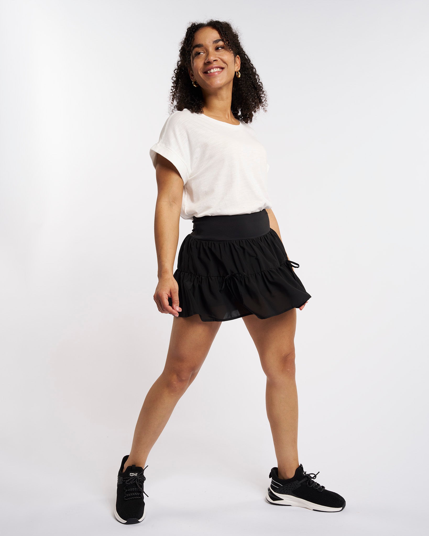Woman wearing black flowy layered tennis skort with high-rise waistband and built-in shorts
