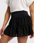Close-up of black tennis skort with wide elastic waistband and tiered layered design