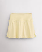 Lemon Butter Stelle classic tennis skirt with a high-waisted fit, slightly flared silhouette, side slits, and bow ribbon details.