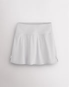 White Stelle classic tennis skirt with a high-waisted fit, slightly flared silhouette, side slits, and bow ribbon details.