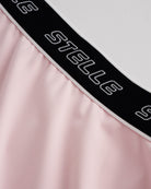 Close-up of ballet pink Stelle tennis skirt showing black logo elastic waistband and soft flared fabric detail.