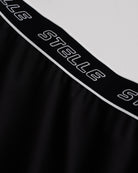 Close-up of black Stelle tennis skirt showing black logo elastic waistband and soft flared fabric detail.
