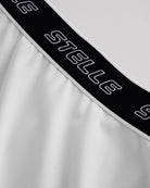 Close-up of white Stelle tennis skirt showing black logo elastic waistband and soft flared fabric detail.