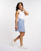 White ruffle V-neck sleeveless polo shirt worn by a woman.
