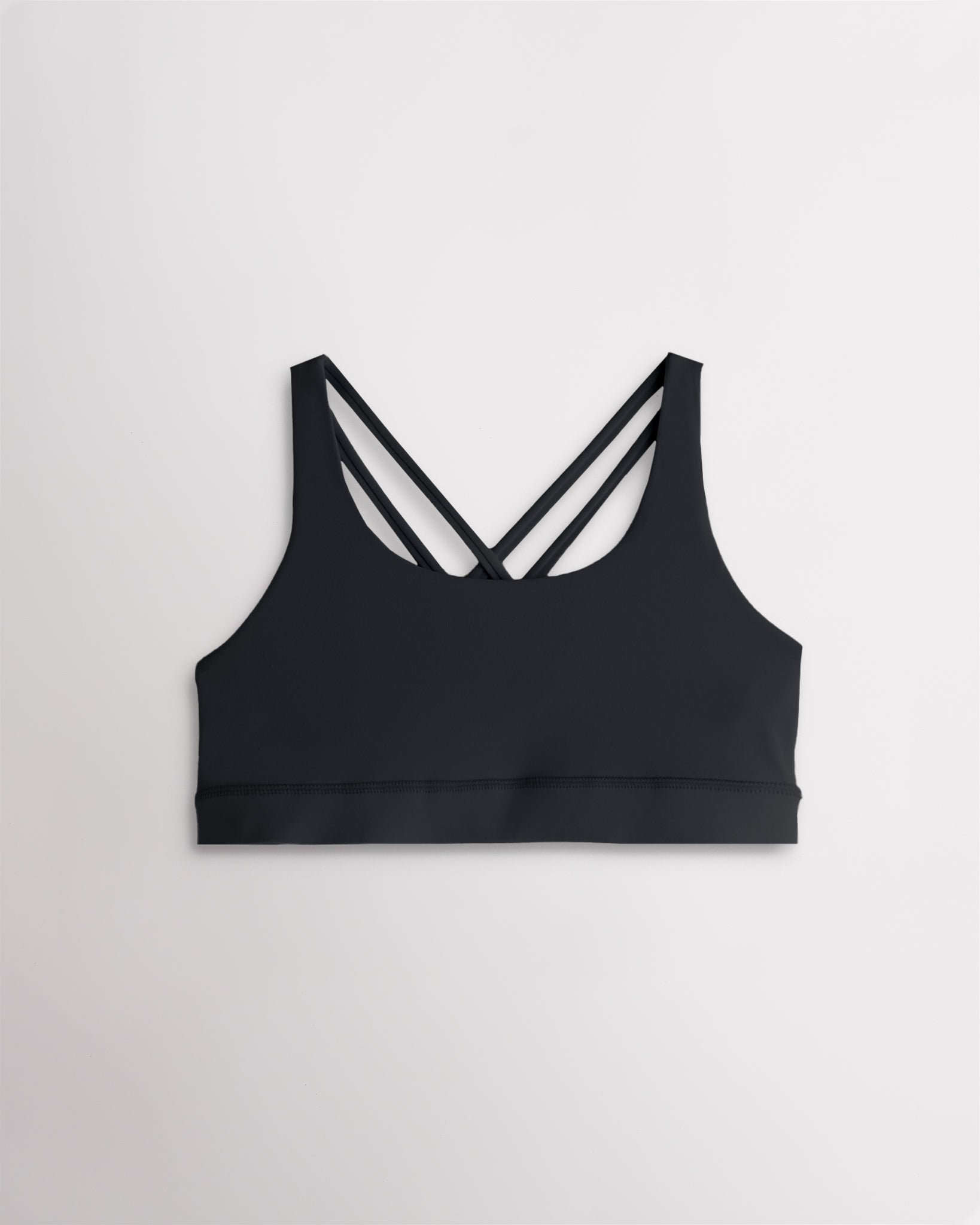 Girls black sports bra with a scoop neckline, supportive band, and strappy criss-cross back design.