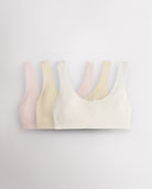Three Stelle girls cotton bralettes in white, soft butter, and whisper pink with wide straps and bow details