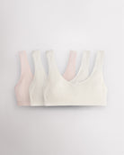 Three Stelle girls cotton bralettes in white and whisper pink with wide straps, soft lining, and small bow detail.