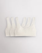 Three Stelle girls cotton bralettes in white with wide straps, soft lining, and small bow detail.