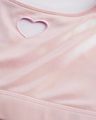 Close-up of pink shimmer crop top showing heart cutout detail, smooth stitching, and iridescent fabric.