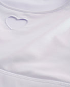 Close-up of white shimmer crop top showing heart cutout detail, smooth stitching, and iridescent fabric.
