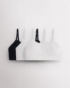 Three Stelle girls seamless cami bras in black and white with slim adjustable straps and soft ribbed bands.