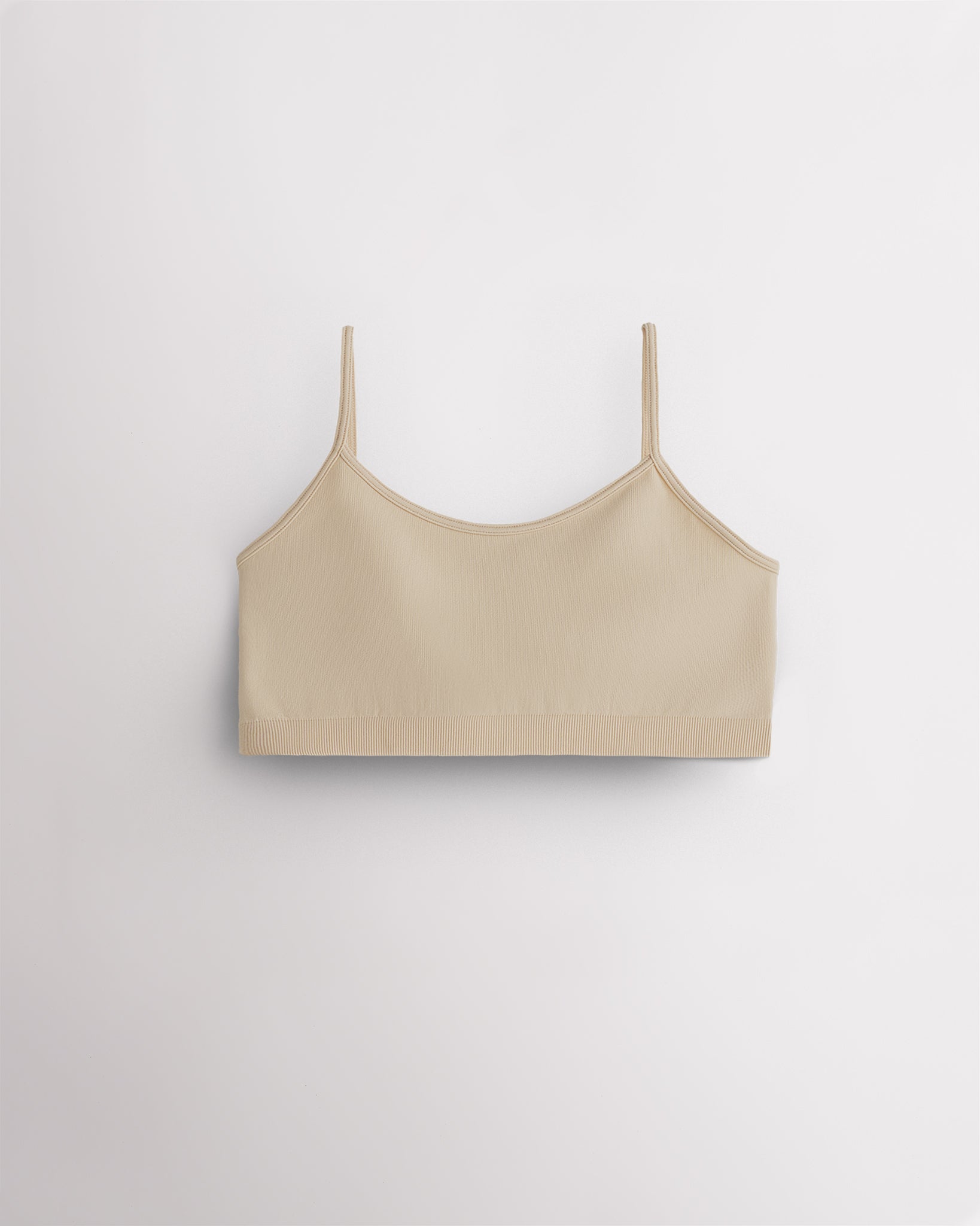 Beige Stelle girls seamless cami bra with thin adjustable straps, shown flat.