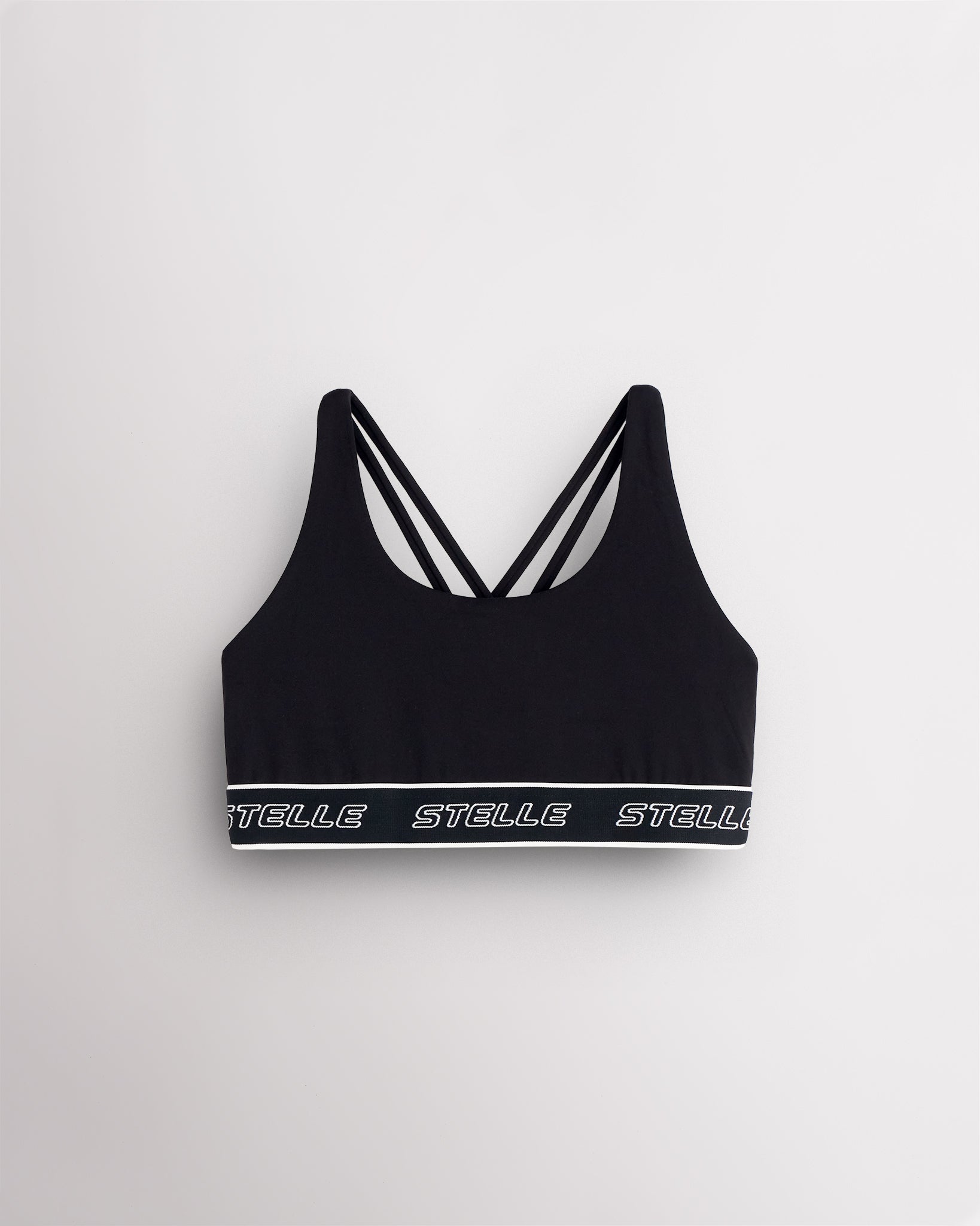 Black Stelle girls sports bra laid flat, showing the scoop neck and logo underband.