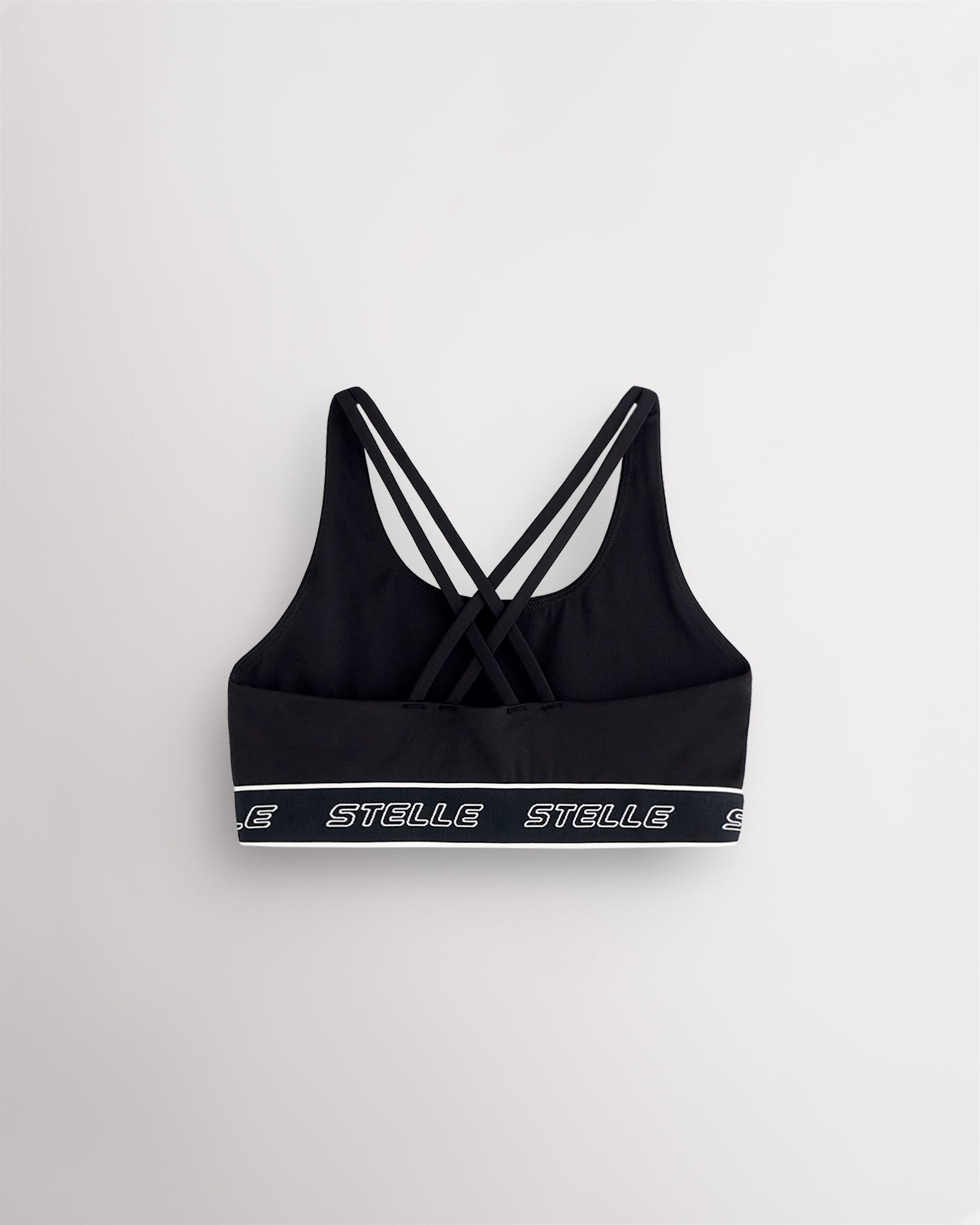 Back of the black Stelle girls sports bra laid flat, showing the criss-cross straps.