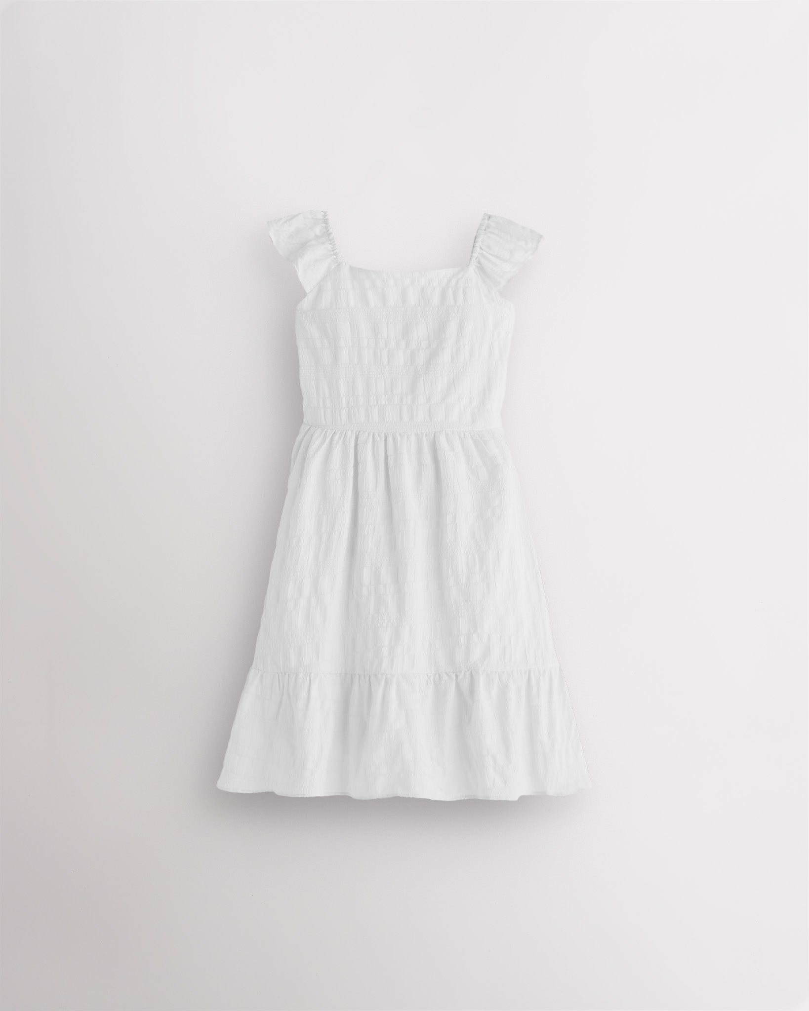 Girls white flutter sleeve sundress with square neckline, smocked waist, and tiered hem, lightweight summer dress front view