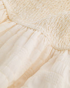 Close-up of butter smocked fabric and gathered waist detail on Stelle girls dress.